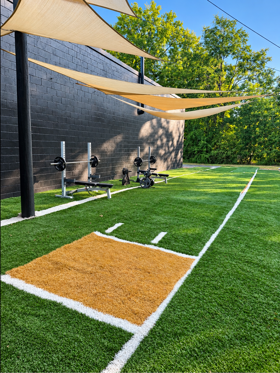 O’s Gym’s outdoor training turf with weight benches, marked lanes, and overhead shade sails